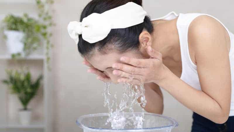 A girl washing off her drugstore oil cleanser with water